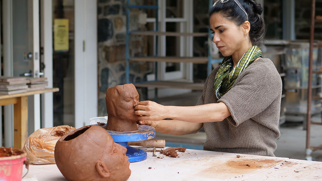 Cristina Cordova sculpting a head in clay, Identity